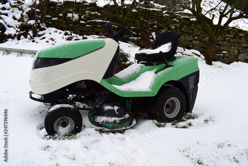 Tractor - lawn mower stands in the snow. Garden tools.