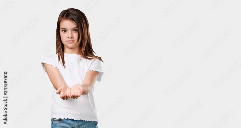 Full body little girl holding something with hands, showing a product, smiling and cheerful, offering an imaginary object Full body little girl holding something with hands, showing a product, smiling and cheerful, offering an imaginary object