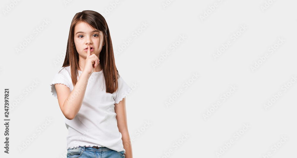 Full body little girl keeping a secret or asking for silence, serious face, obedience concept