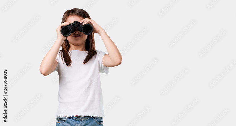 Full body little girl surprised and amazed, looking with binoculars in the distance something interesting, concept of future opportunity Full body little girl surprised and amazed, looking with binoculars in the distance something interesting, concept of future opportunity