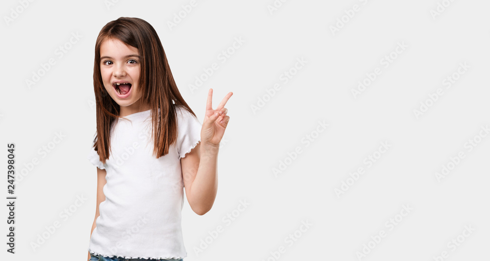 Full body little girl fun and happy, positive and natural, makes a gesture of victory, peace concept Full body little girl fun and happy, positive and natural, makes a gesture of victory, peace concept