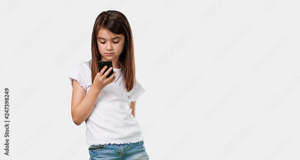 Full body little girl closeup of hand touching a mobile, using internet and social networks, positive feeling of future and modernity Full body little girl closeup of hand touching a mobile, using internet and social networks, positive feeling of future and modernity