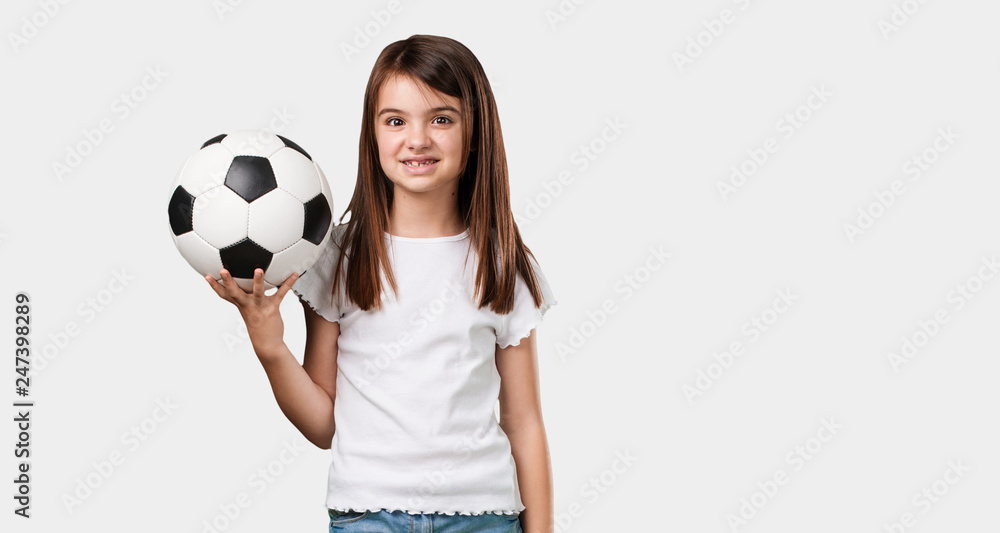 Full body little girl smiling and happy, holding a soccer ball, competitive attitude, excited to play a game