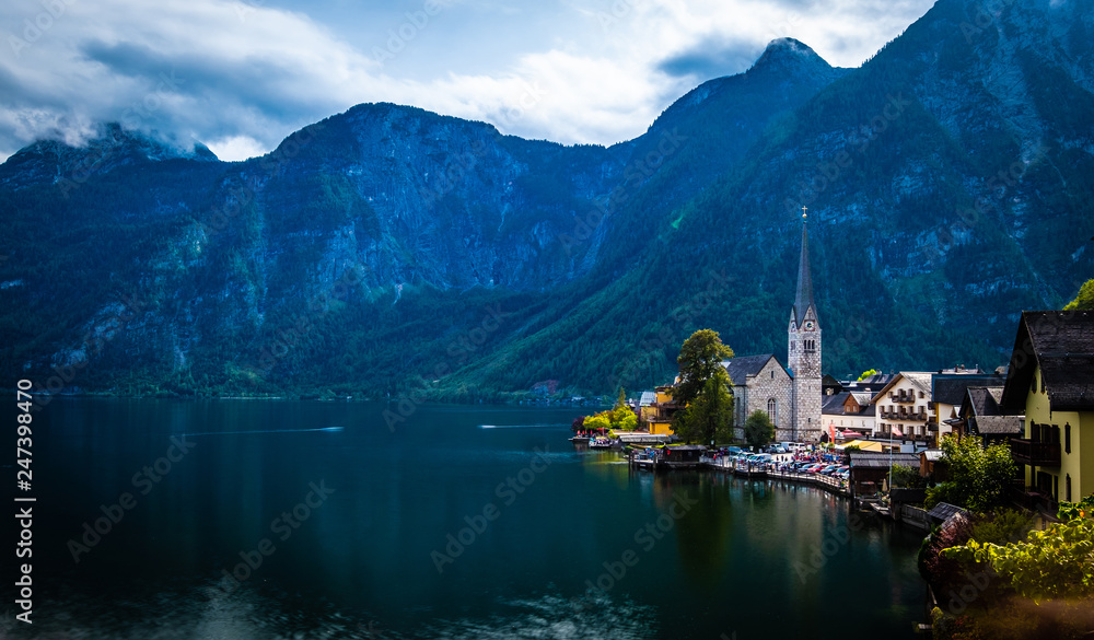 Dramatic evening scenery of high rocky mountains and Hallstatt city at the wide lake