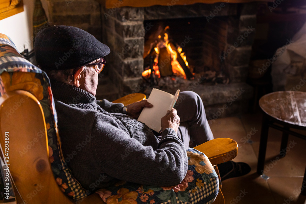 Relaxed senior man sitting in front of the fireplace Stock Photo