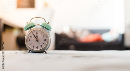 White alarm clock on the bed, morning, copyspace