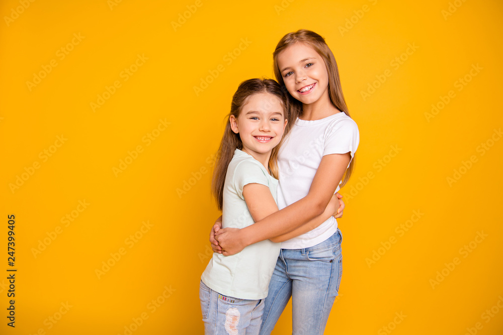 Portrait of two nice-looking cute winsome sweet attractive lovely pretty cheerful cheery positive caucasian straight-haired girls cuddling isolated over bright vivid shine yellow background Portrait of two nice-looking cute winsome sweet attractive lovely pretty cheerful cheery positive caucasian straight-haired girls cuddling isolated over bright vivid shine yellow background