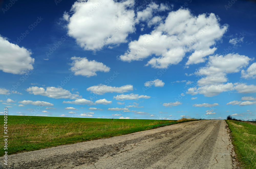 laconic landscape with road, field and sky with clouds