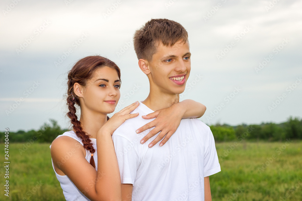 young beautiful cute couple girl and guy are standing arm in arm on a background of nature, the concept of the relationship young beautiful cute couple girl and guy are standing arm in arm on a background of nature, the concept of the relationship