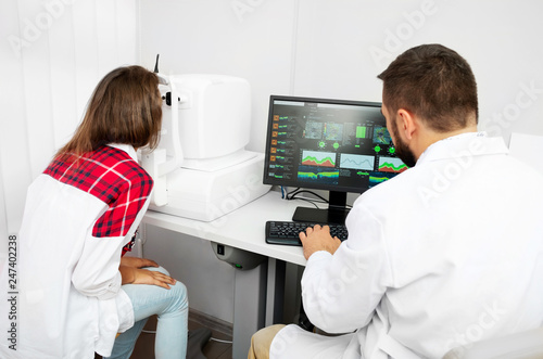 Teenage girl udergoes eye survey with doctor on tomograph in ophthalmologic clinic