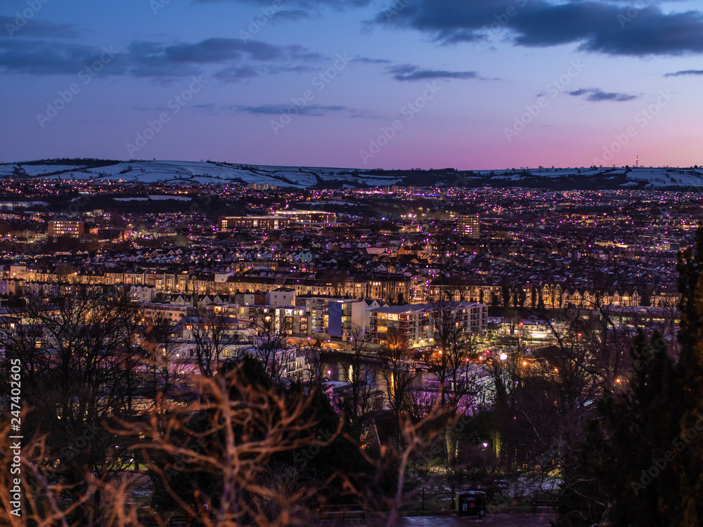 Night city scenic with glowing city lights & snowy hilltops, Bristol UK