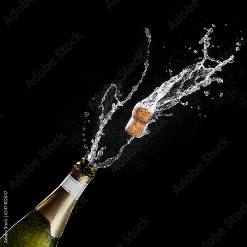 Opening a bottle of champagne. The celebration theme with splashing champagne isolated on black background. Traffic's flying.