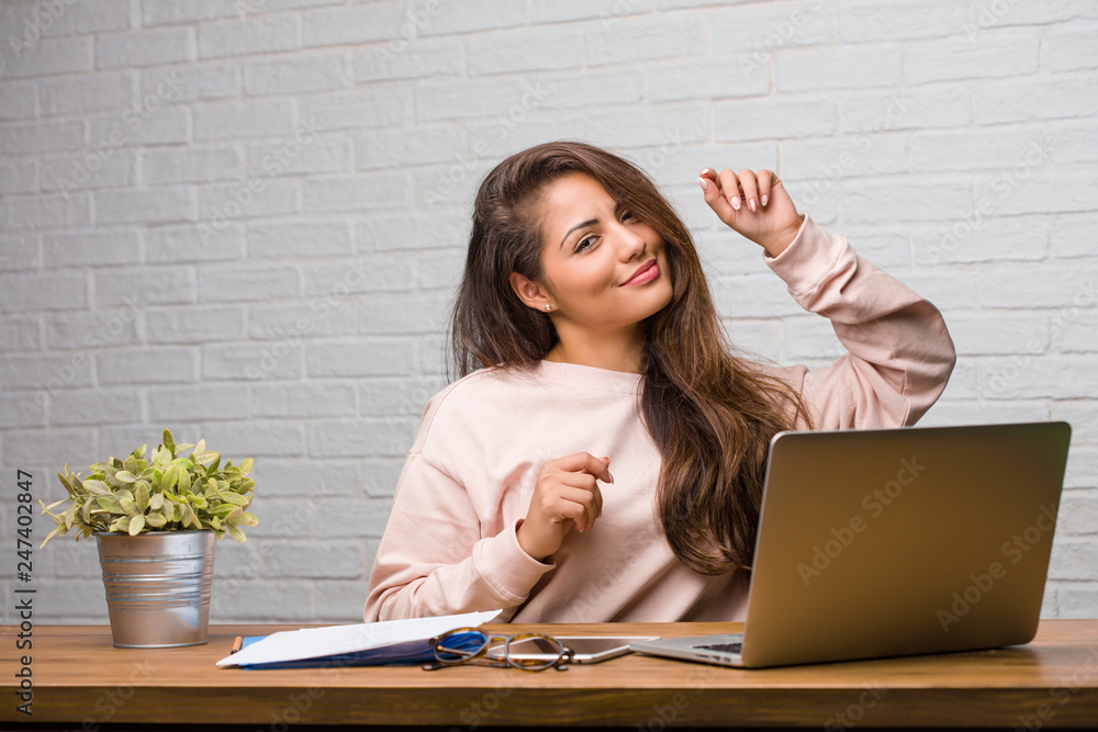 Portrait of young student latin woman sitting on her desk listening to music, dancing and having fun, moving, shouting and expressing happiness, freedom concept Portrait of young student latin woman sitting on her desk listening to music, dancing and having fun, moving, shouting and expressing happiness, freedom concept