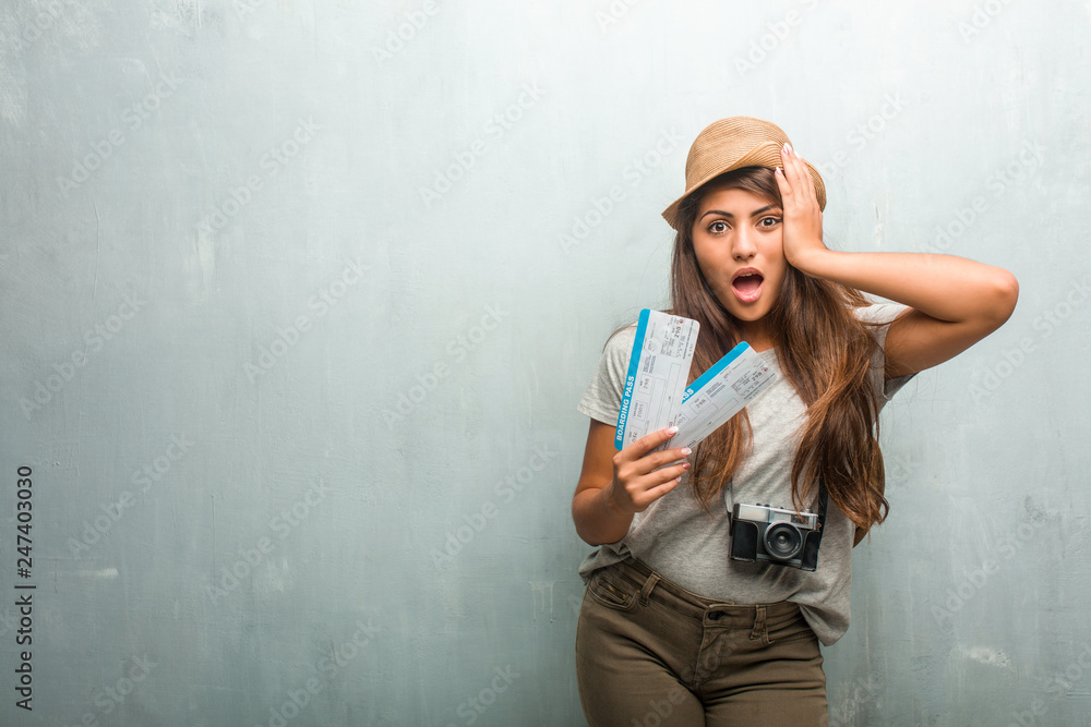 Portrait of young traveler latin woman against a wall frustrated and desperate, angry and sad with hands on head. Holding a boarding pass. Portrait of young traveler latin woman against a wall frustrated and desperate, angry and sad with hands on head. Holding a boarding pass.
