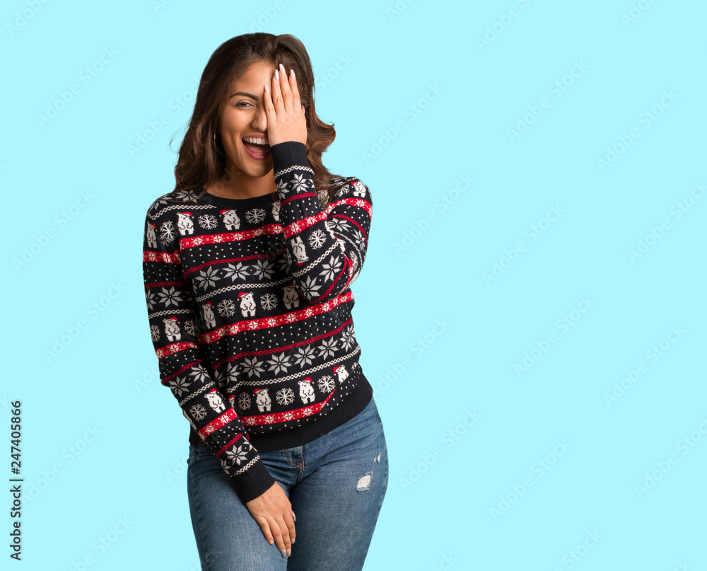 Full body young woman wearing a christmas jersey shouting happy and covering face with hand Full body young woman wearing a christmas jersey shouting happy and covering face with hand