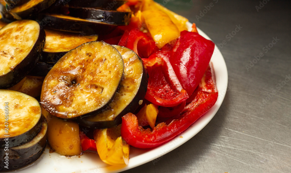 Steamed and roasted vegetables on a barbecue eggplant and red pepper on a plate, close-up Steamed and roasted vegetables on a barbecue eggplant and red pepper on a plate, close-up