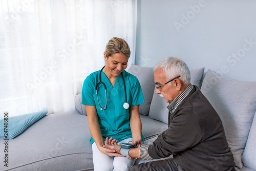Heart work. Attentive caregiver using tonometer while elder man having breath problem