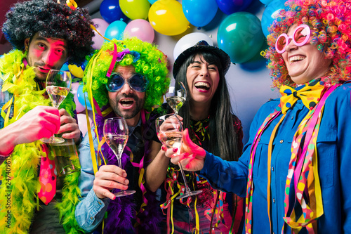 Lachende Freunde in bunten Kost  men trinken Sekt bei einer Karneval party .