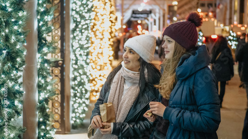 Two girls in New York look at Christmas decorated shop windows