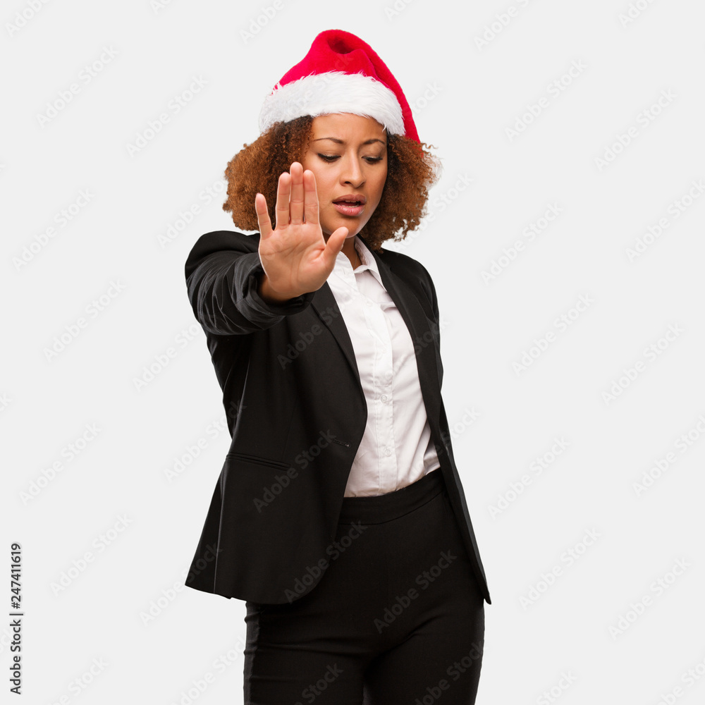 Young business black woman wearing a chirstmas santa hat putting hand in front Young business black woman wearing a chirstmas santa hat putting hand in front