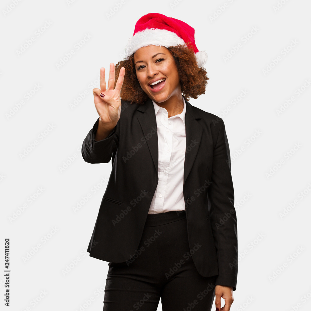 Young business black woman wearing a chirstmas santa hat showing number three Young business black woman wearing a chirstmas santa hat showing number three