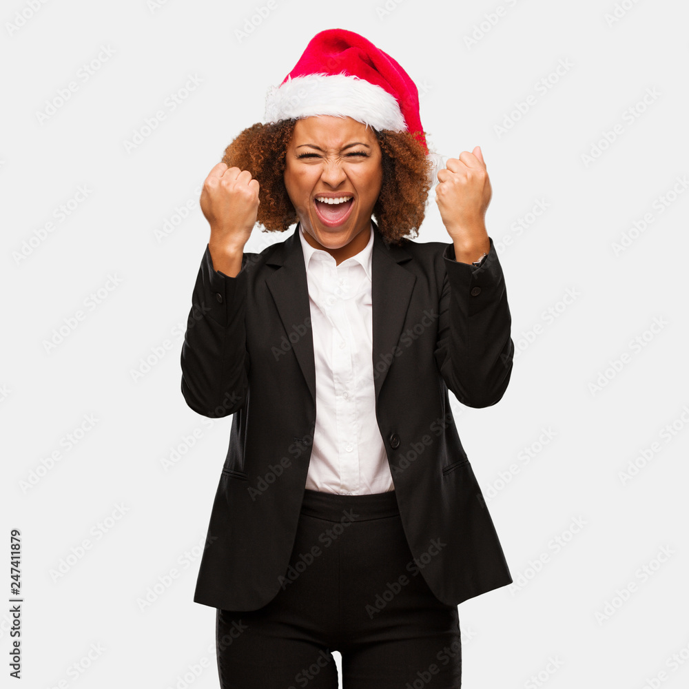 Young business black woman wearing a chirstmas santa hat surprised and shocked Young business black woman wearing a chirstmas santa hat surprised and shocked