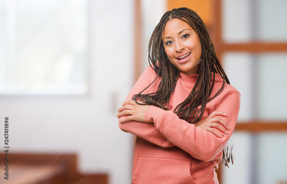 Portrait of a young black woman wearing braids crossing his arms, smiling and happy, being confident and friendly Portrait of a young black woman wearing braids crossing his arms, smiling and happy, being confident and friendly