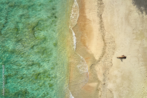 Top view at tropical sand beach with sunbathing girl