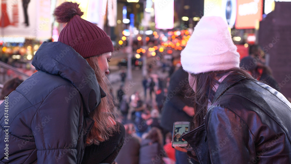 Two girls in New York enjoy the amazing view over Times Square by night Two girls in New York enjoy the amazing view over Times Square by night