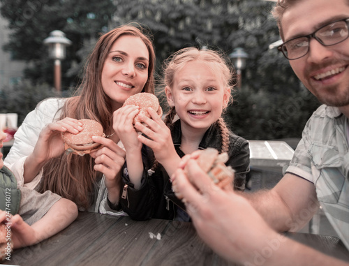 close up. happy family with hamburgers, sitting at a table