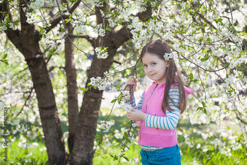 Cute girl in a blooming cherry tree garden Cute girl in a blooming cherry tree garden