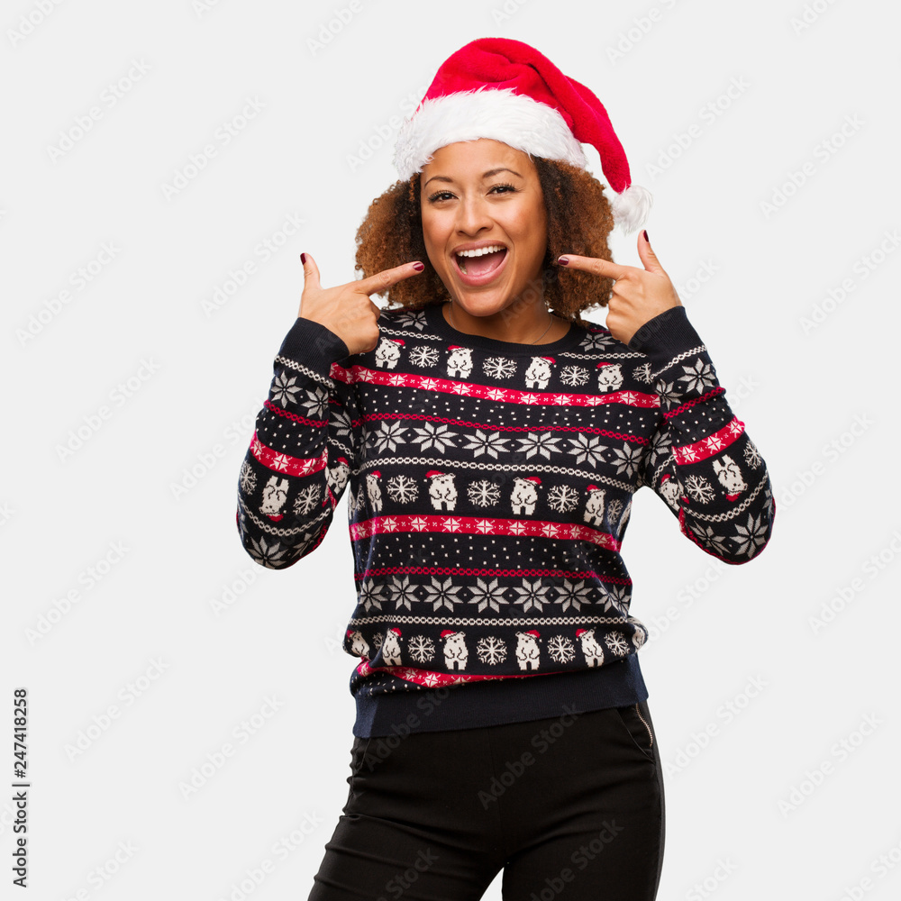 Young black woman in a trendy christmas sweater with print smiles, pointing mouth Young black woman in a trendy christmas sweater with print smiles, pointing mouth