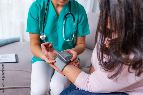 Young nurse measuring blood pressure of elderly woman at home. © Dragana Gordic