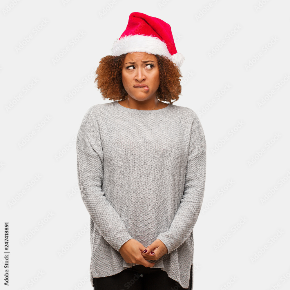 Young black woman wearing a santa hat thinking about an idea Young black woman wearing a santa hat thinking about an idea