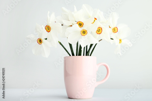 White narcissus flowers in mug on grey background