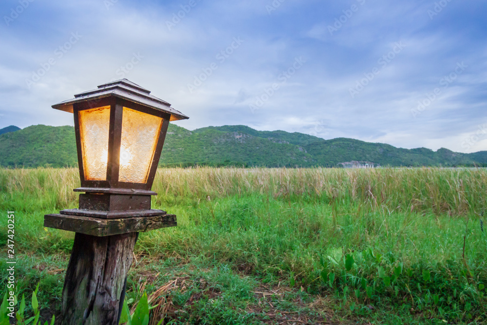 Orange light from Old lamp stand with man and mountain background at morning time Orange light from Old lamp stand with man and mountain background at morning time