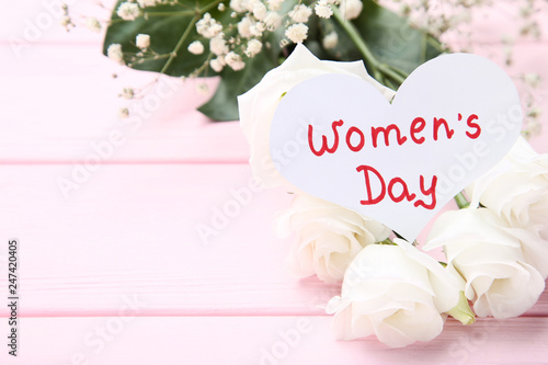 Text Women's Day with eustoma and gypsophila flowers on pink wooden table