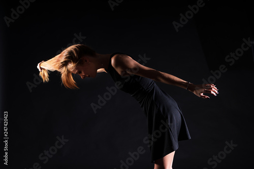 Caucasian white female model portrait. The wind blowing the long blonde hair off on beautiful girl. Woman posing studio shot on a black background