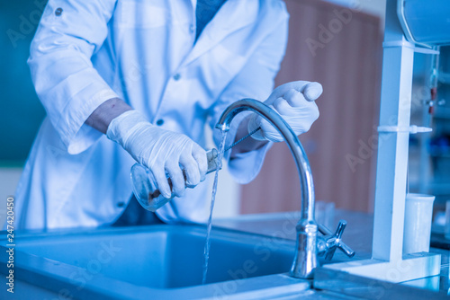 scientist wash beaker from poisonous acid after experiments b photo