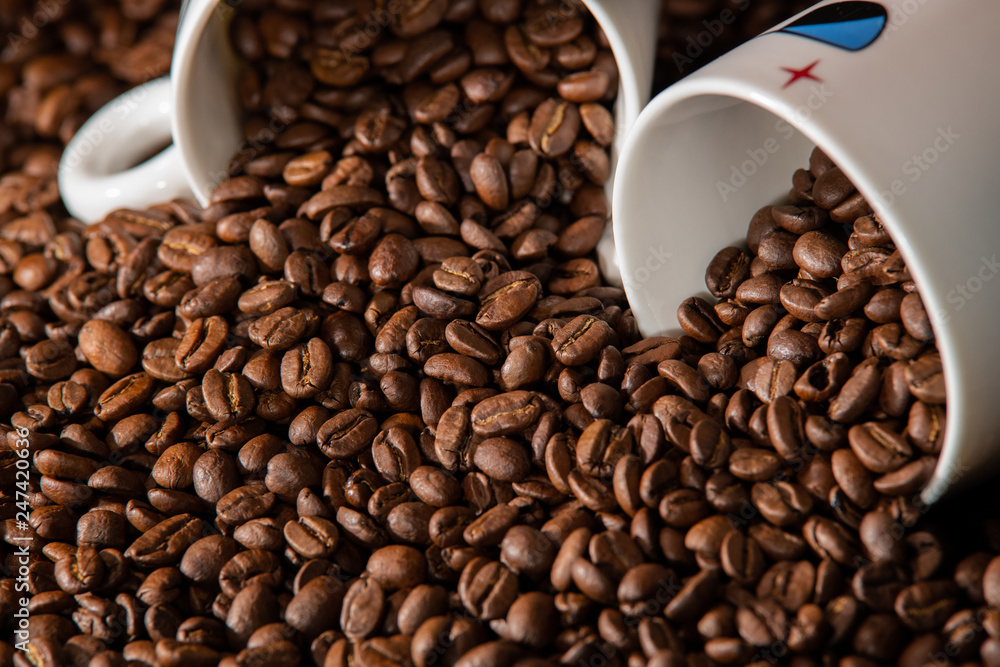 white cups with a pattern and grains of coffee on a black background white cups with a pattern and grains of coffee on a black background