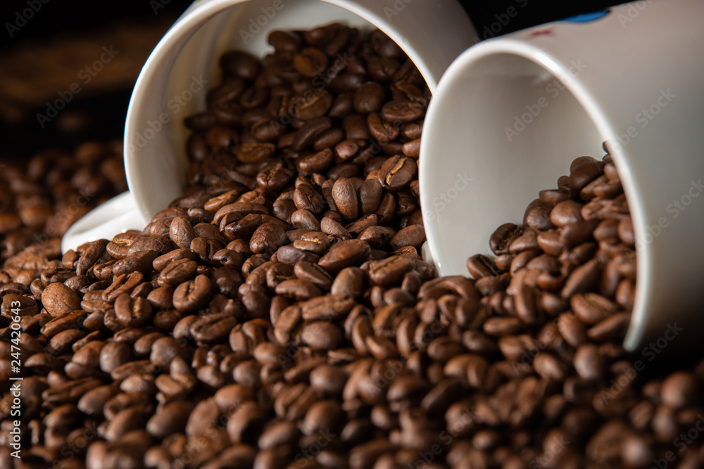 white cups with a pattern and grains of coffee on a black background white cups with a pattern and grains of coffee on a black background