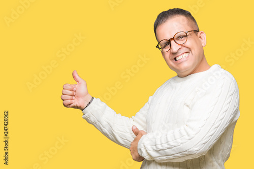 Middle age arab man wearing glasses over isolated background Looking proud, smiling doing thumbs up gesture to the side