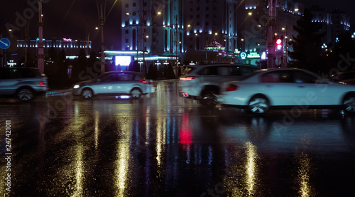 Ashgabat, Turkmenistan. Movement on a junction in rush our at 21:00. Rainy weather, city lights reflected on a surface (asphalt) Out of focus, motion blur.