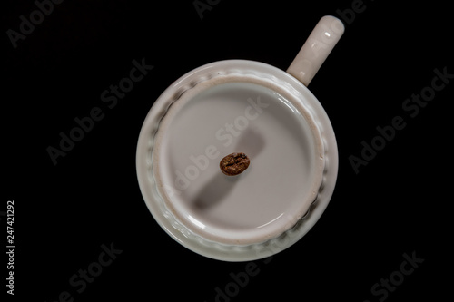white cups with a pattern and grains of coffee on a black background