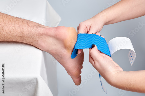doctor physiotherapist hands applying kinesio medical taping on the ankle