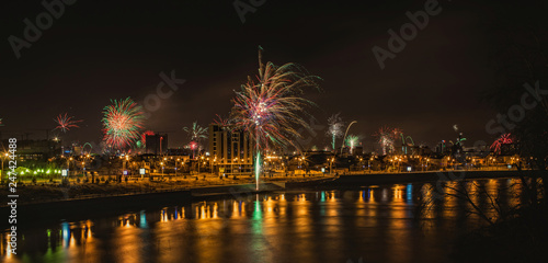 panorama of fireworks over the night town reflected in the water © Nikita