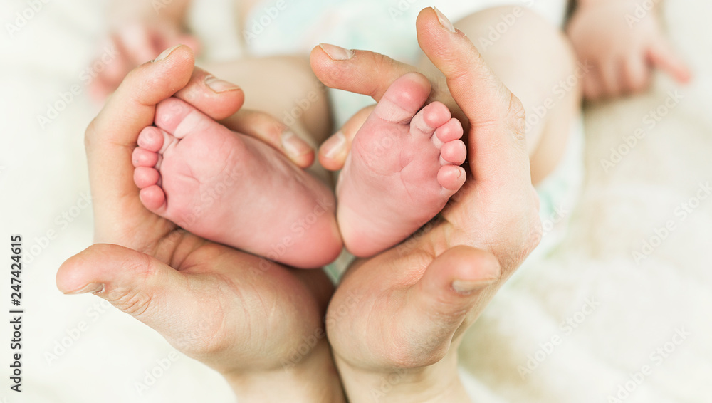 hand holding newborn baby feet in hear shape. Macro photo of adorable little boy toes with plush lining cozy blanket background hand holding newborn baby feet in hear shape. Macro photo of adorable little boy toes with plush lining cozy blanket background