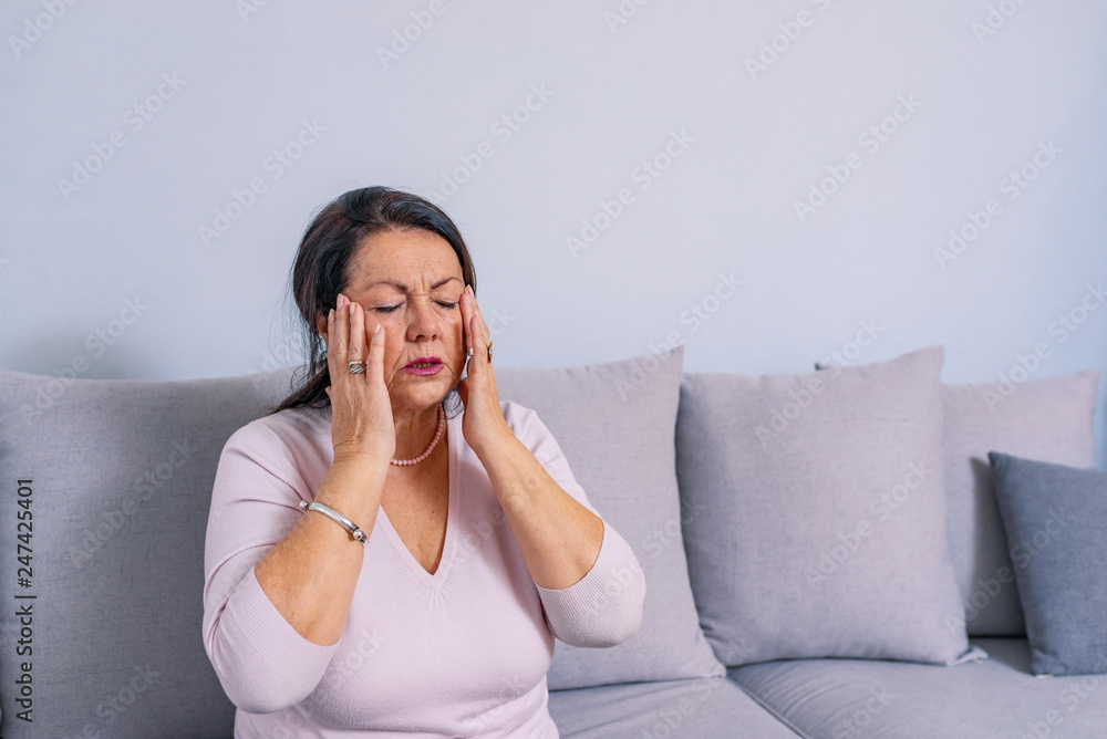 Woman suffering from stress or a headache grimacing in pain Woman suffering from stress or a headache grimacing in pain