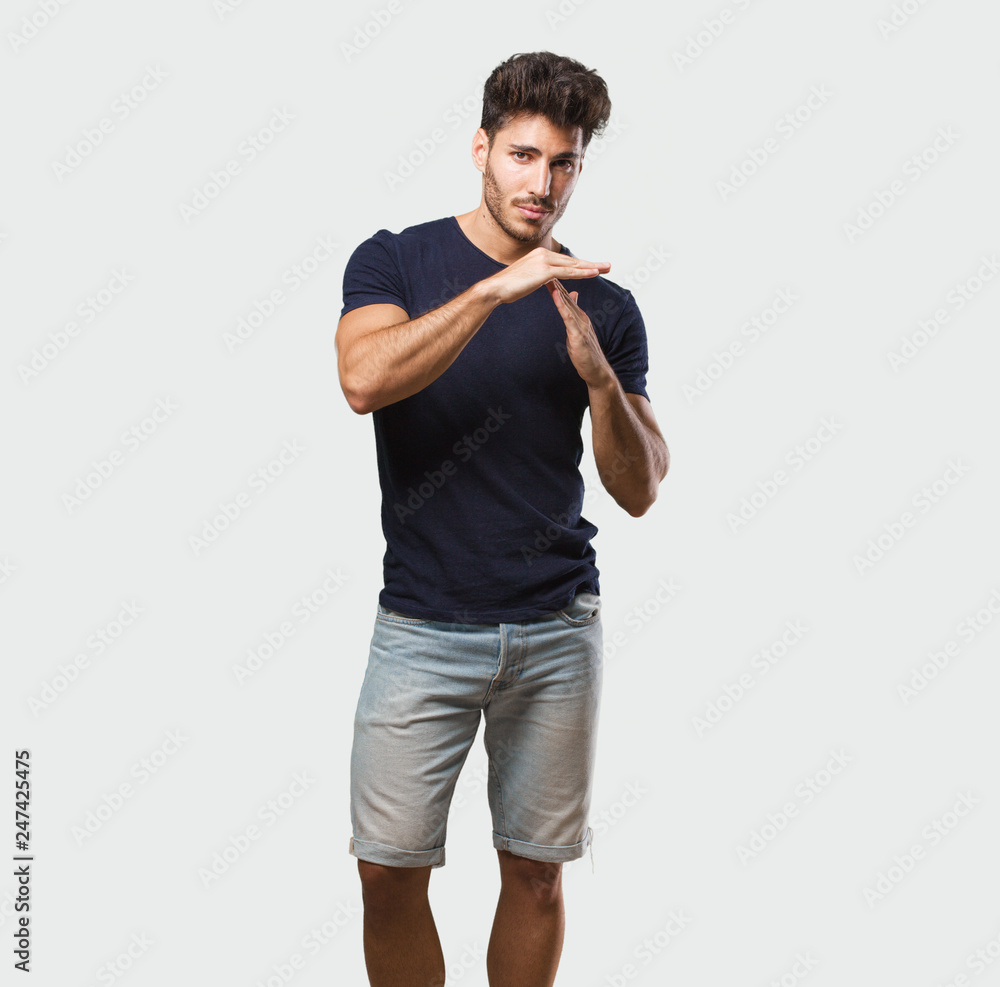 Young handsome man standing tired and bored, making a timeout gesture, needs to stop because of work stress, time concept Young handsome man standing tired and bored, making a timeout gesture, needs to stop because of work stress, time concept
