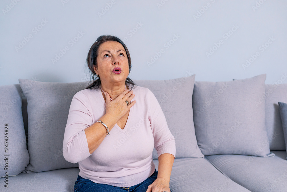 Senior woman at home feeling unwell. A senior woman touching her neck. Senior woman at home feeling unwell. A senior woman touching her neck.